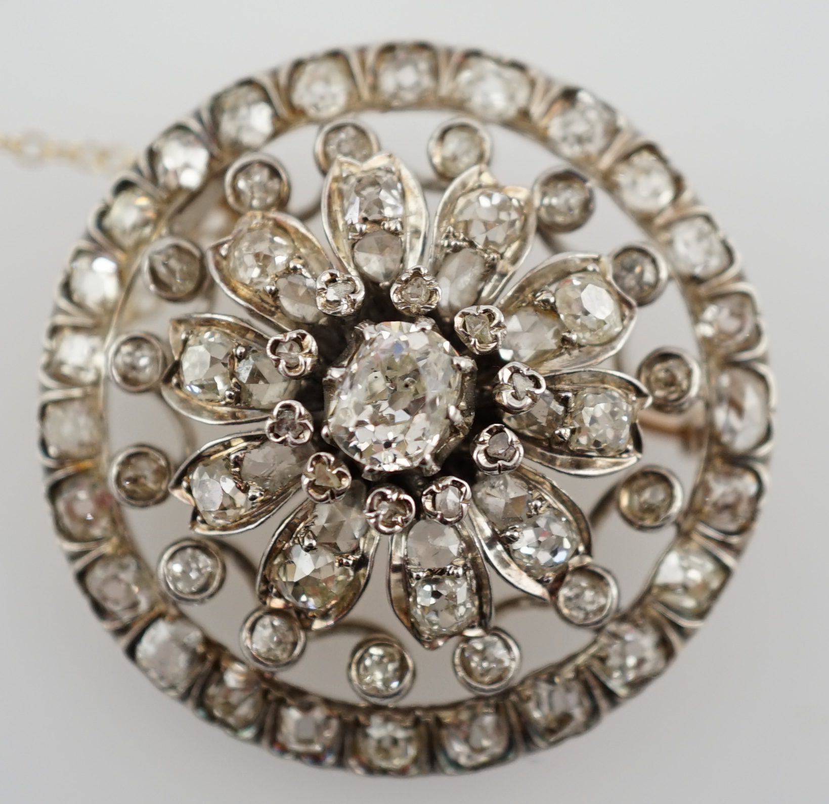 An Edwardian pierced gold and diamond cluster set circular brooch, with central cushion cut stone, diameter 34mm, gross weight 14.4 grams. Condition - fair to good